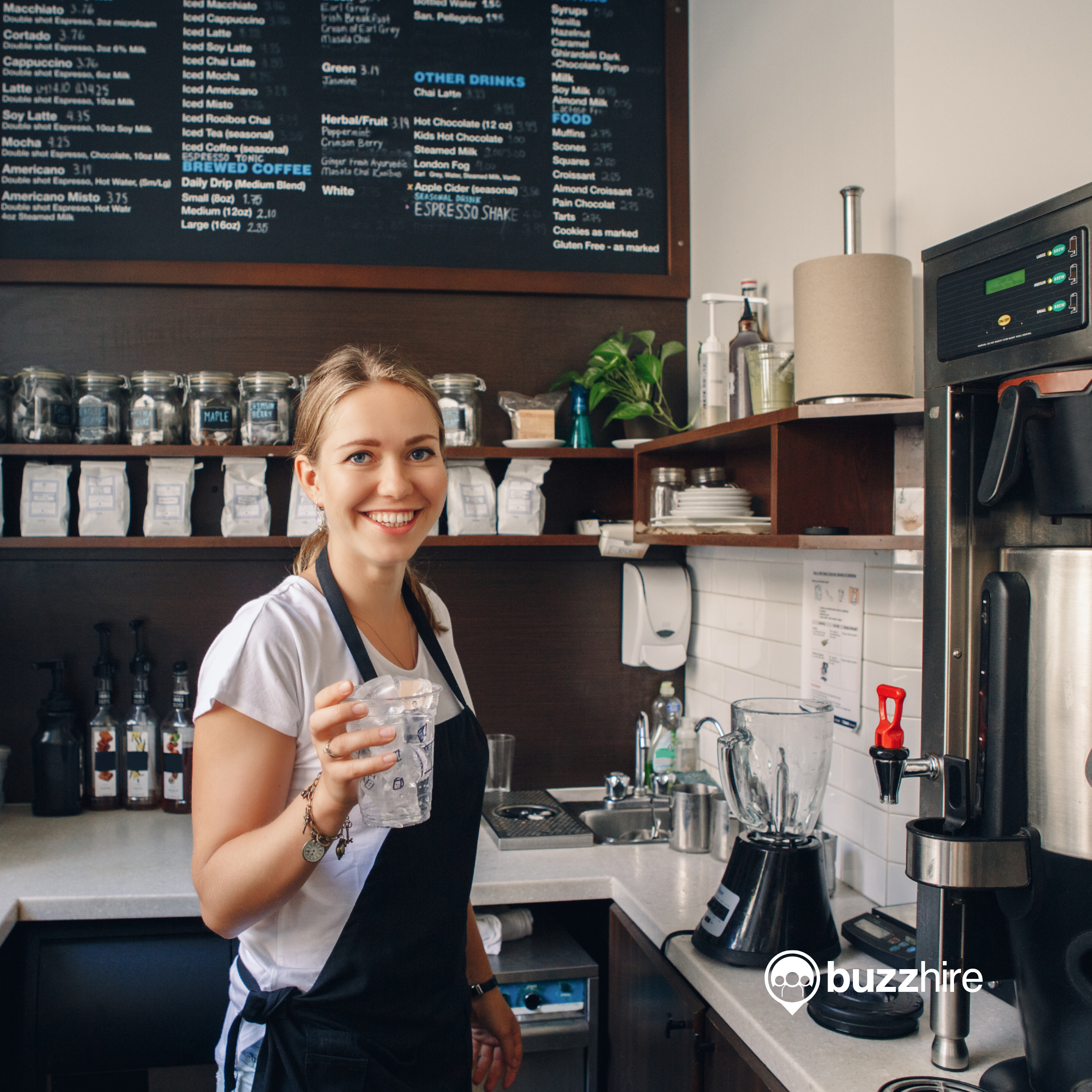 female barista smiling in a cafe making coffee